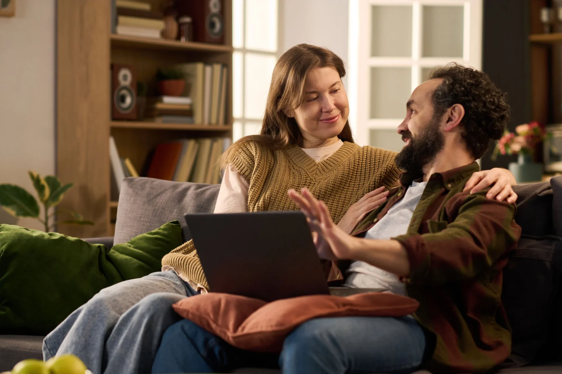 Couple sitting together on a sofa with a laptop open in front of them during a video session