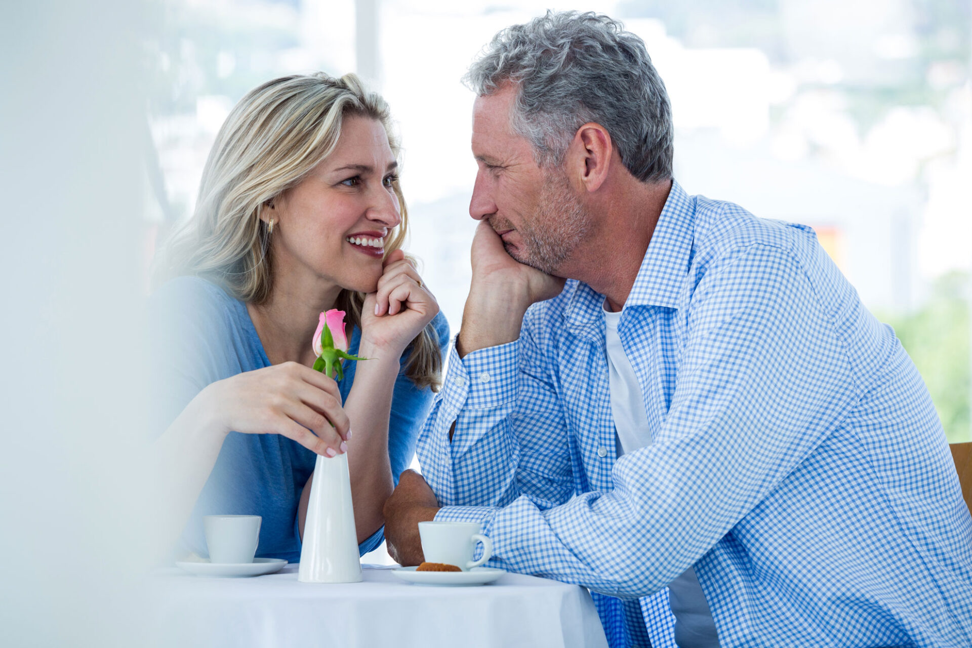 Romantic senior couple talking across a restaurant table with a rose between them
