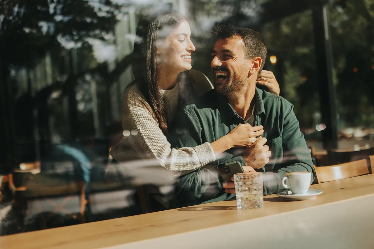 Couple laughing over coffee in a cafe on a first date after meeting on Age Gap Dating