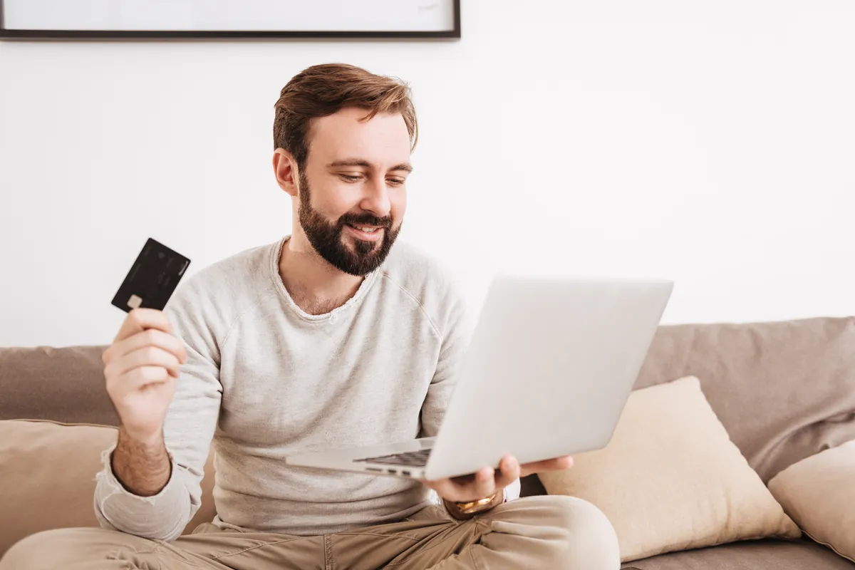 Man holding a card to buy AlltverLadies credits on his laptop
