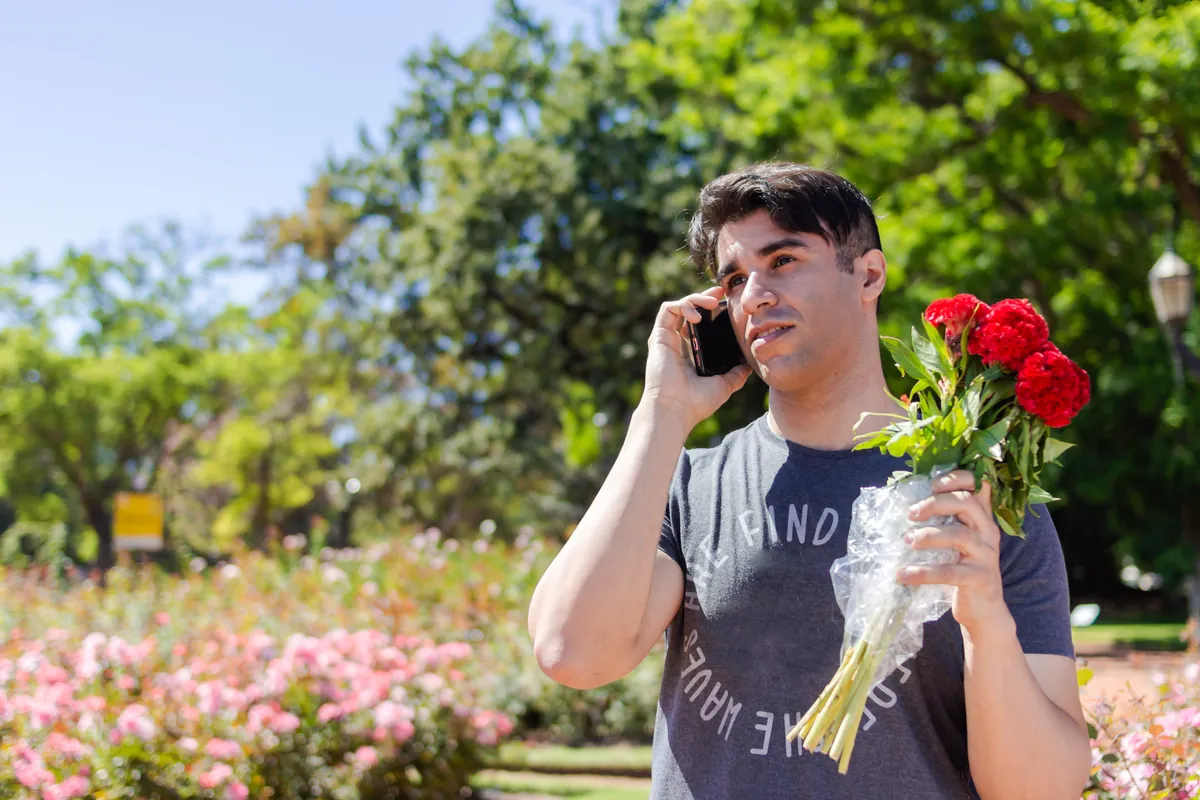 Man with red roses on the phone, waiting for a date