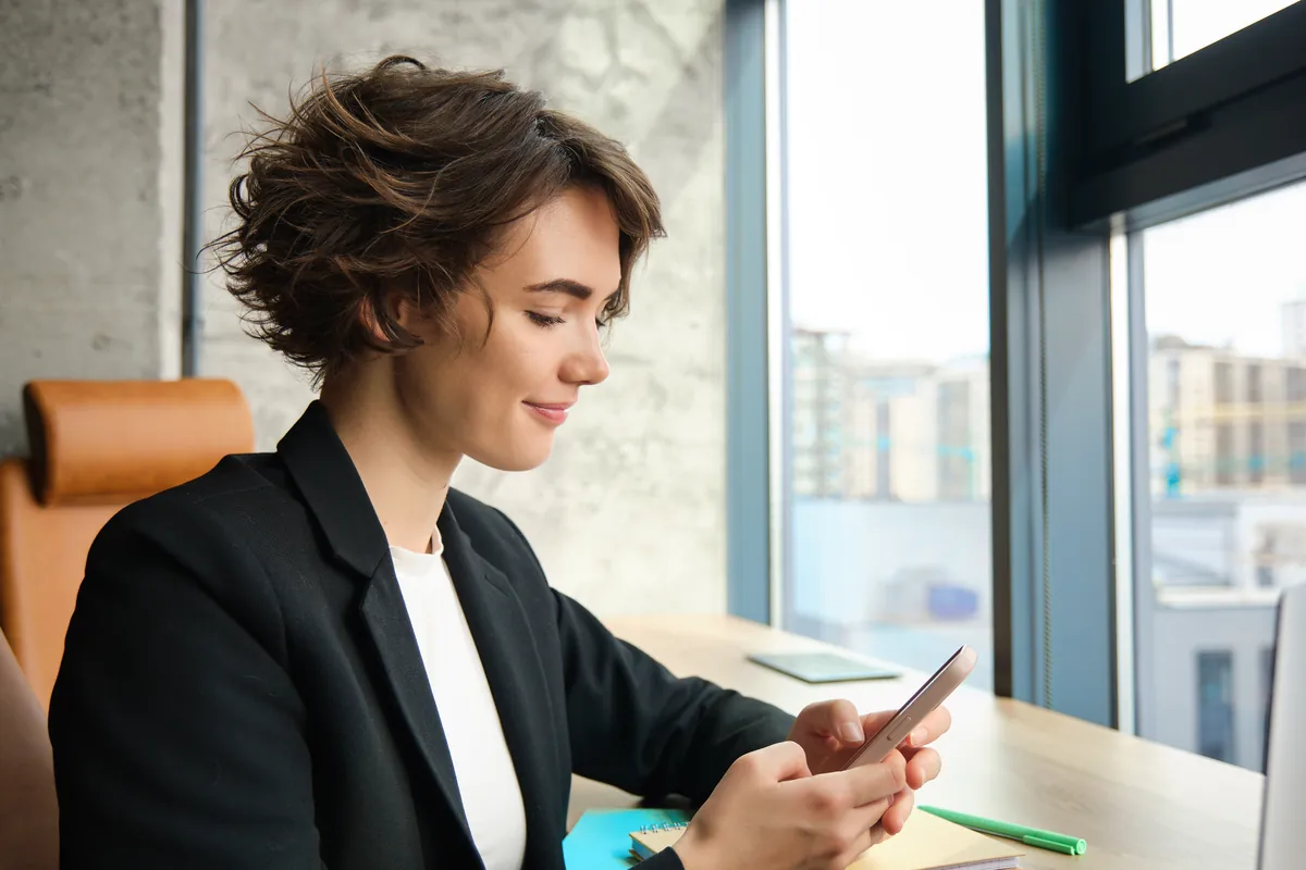 Professional woman checking her elite dating app application on her phone at the office