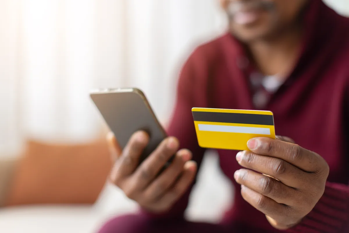 Hands holding a phone and a credit card to pay for an elite dating app membership