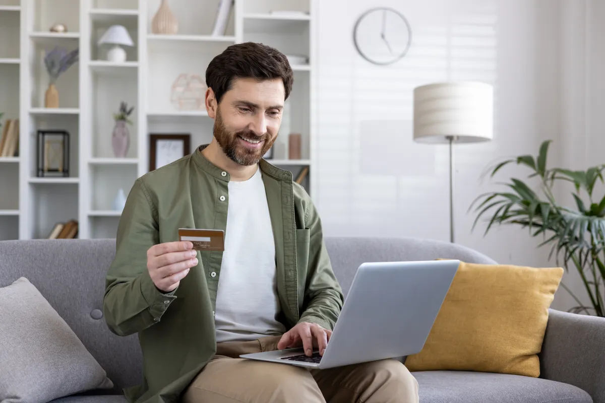 Man holding a credit card at his laptop to buy My Transgender Date Premium