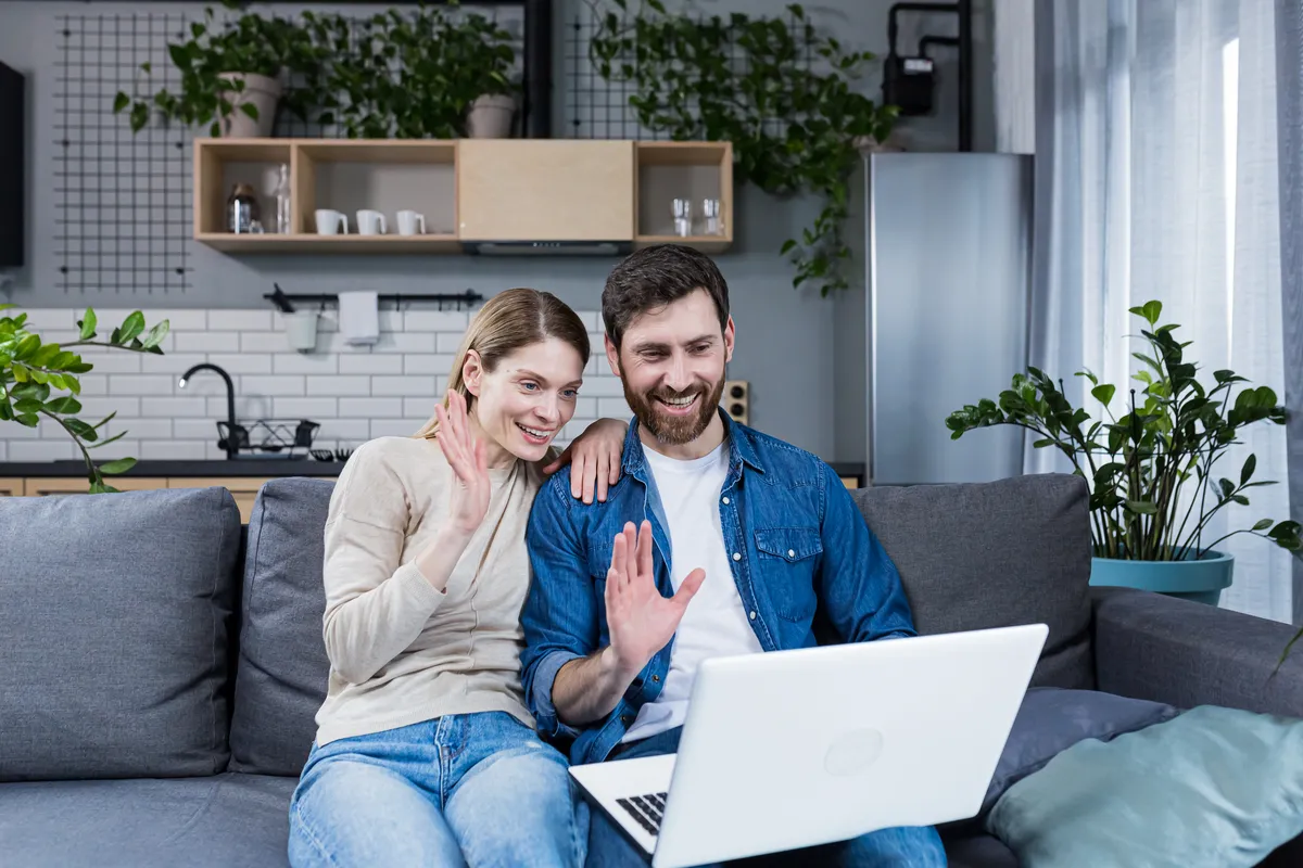 Couple waving at a laptop during a video call, a step SingleParentMatch suggests before a first meeting