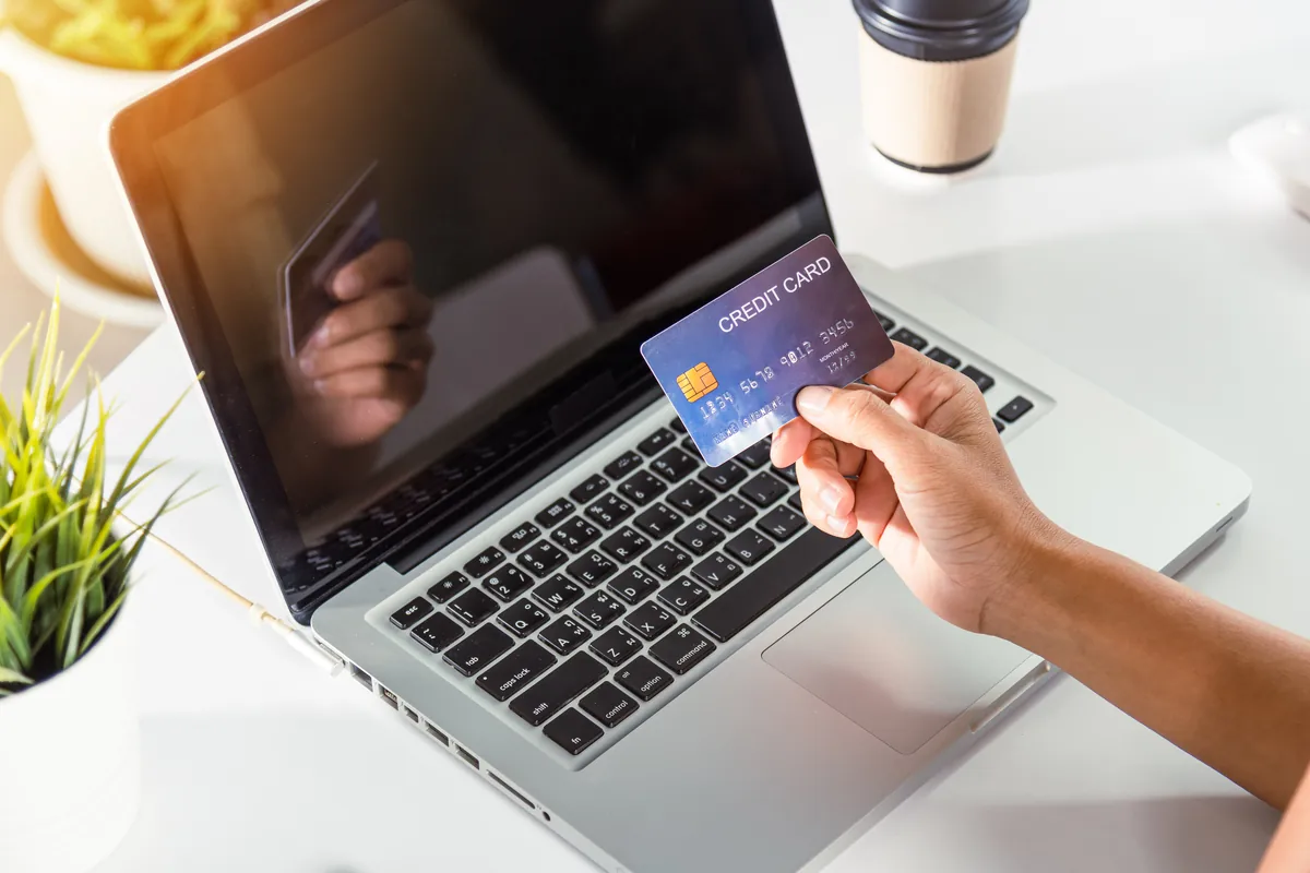 Hands holding a credit card over a laptop while buying credits on a Ukrainian dating site