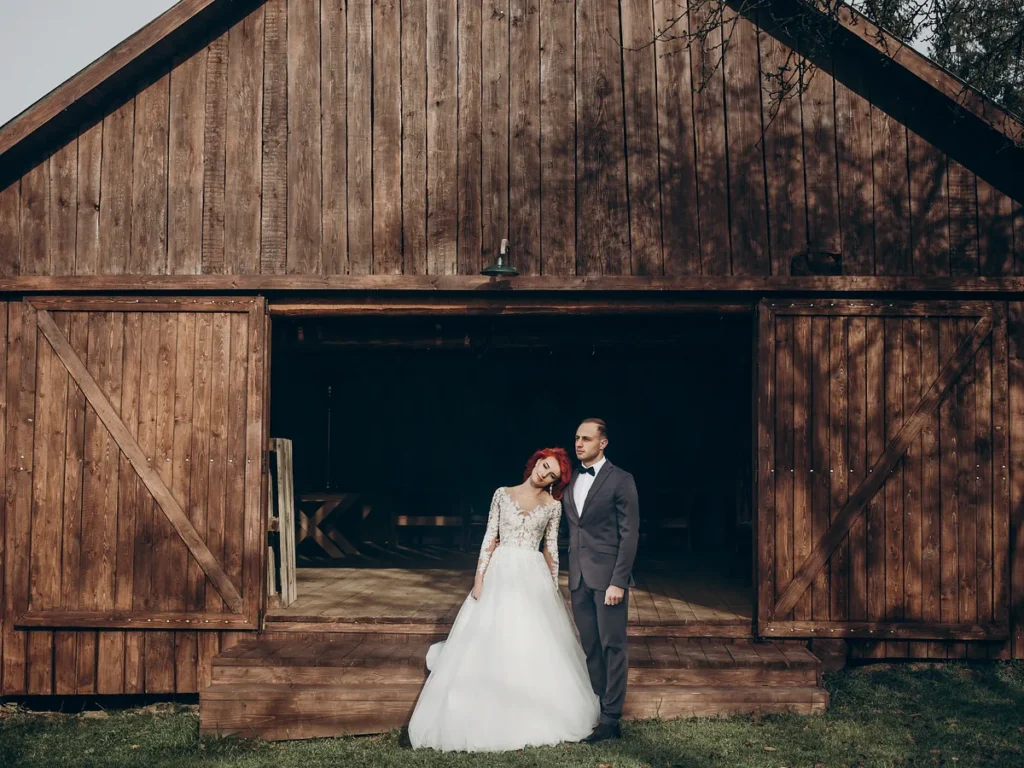 Bride and groom standing in front of a wooden barn