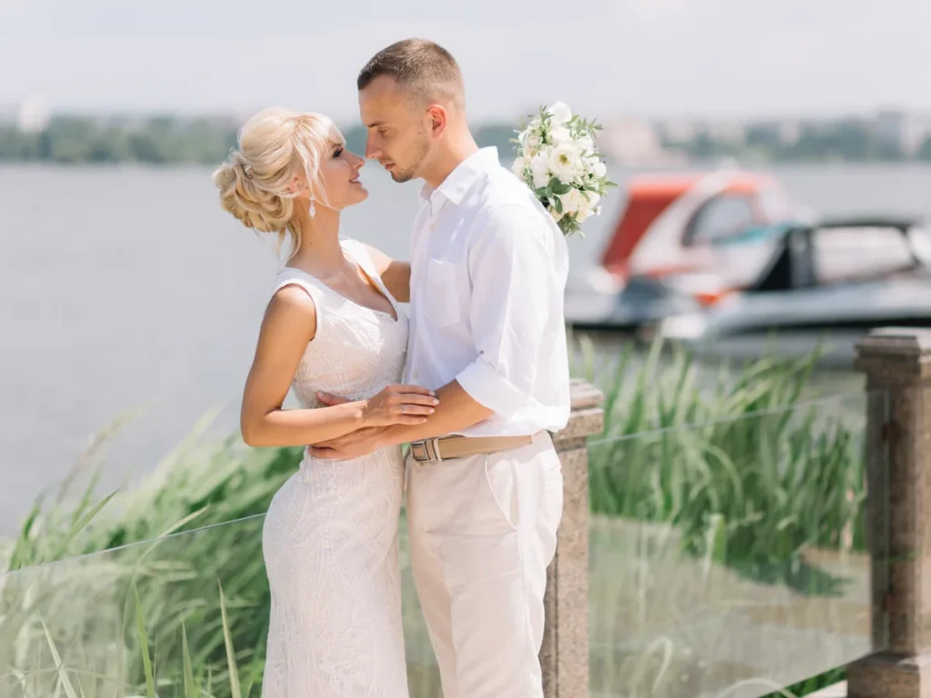 Bride and groom kissing beside a lakeside marina