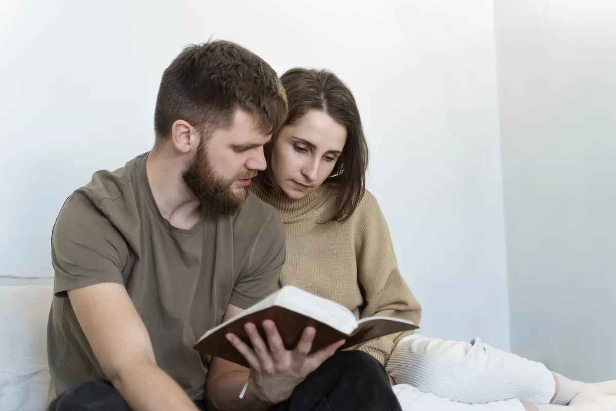 Couple reading the Bible together on the sofa at home