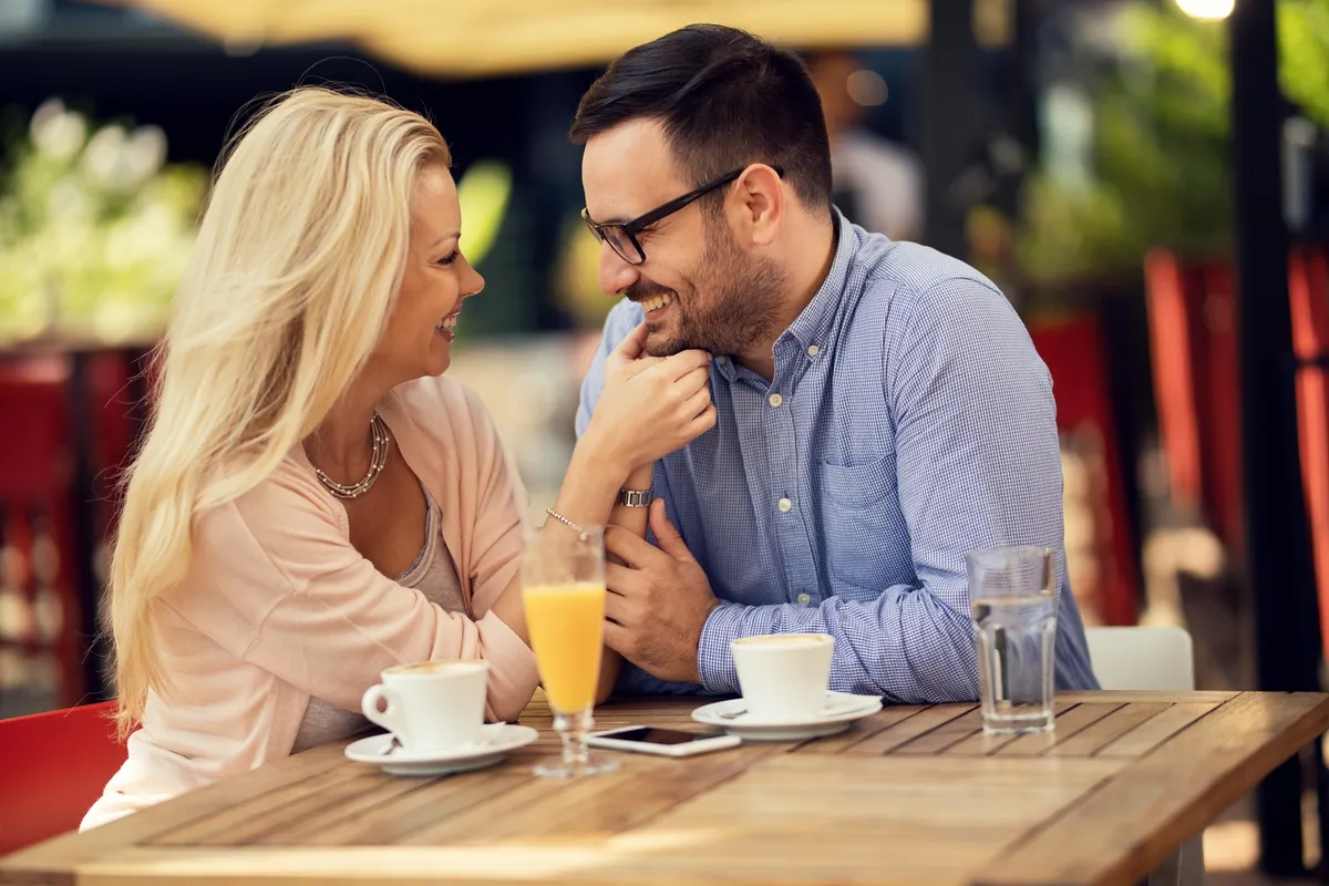 Couple laughing on a first coffee date at an outdoor cafe