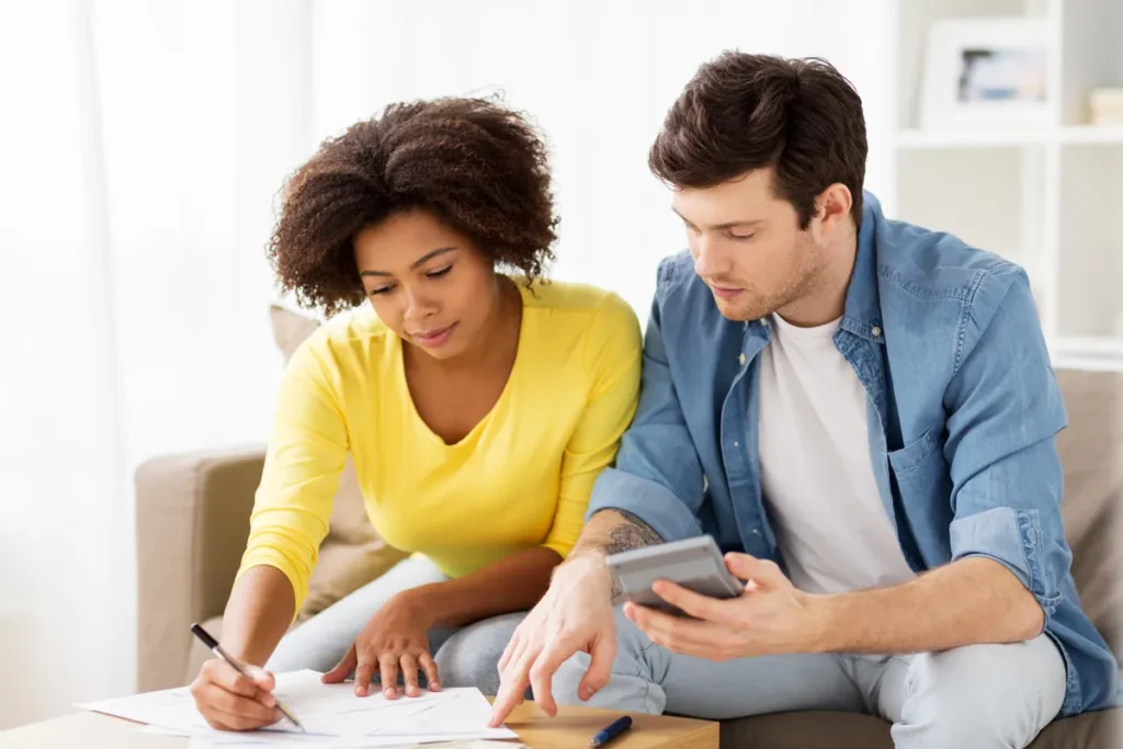 Couple working out costs with a calculator and notes at home