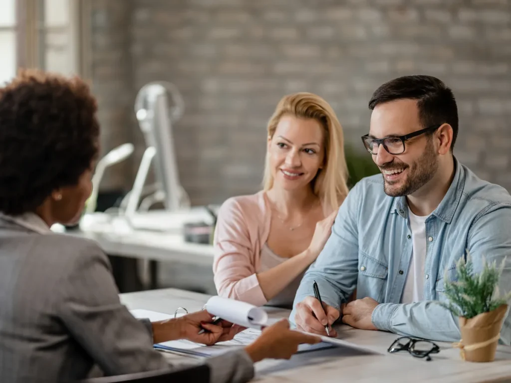 Couple discussing an agreement with an advisor across a desk