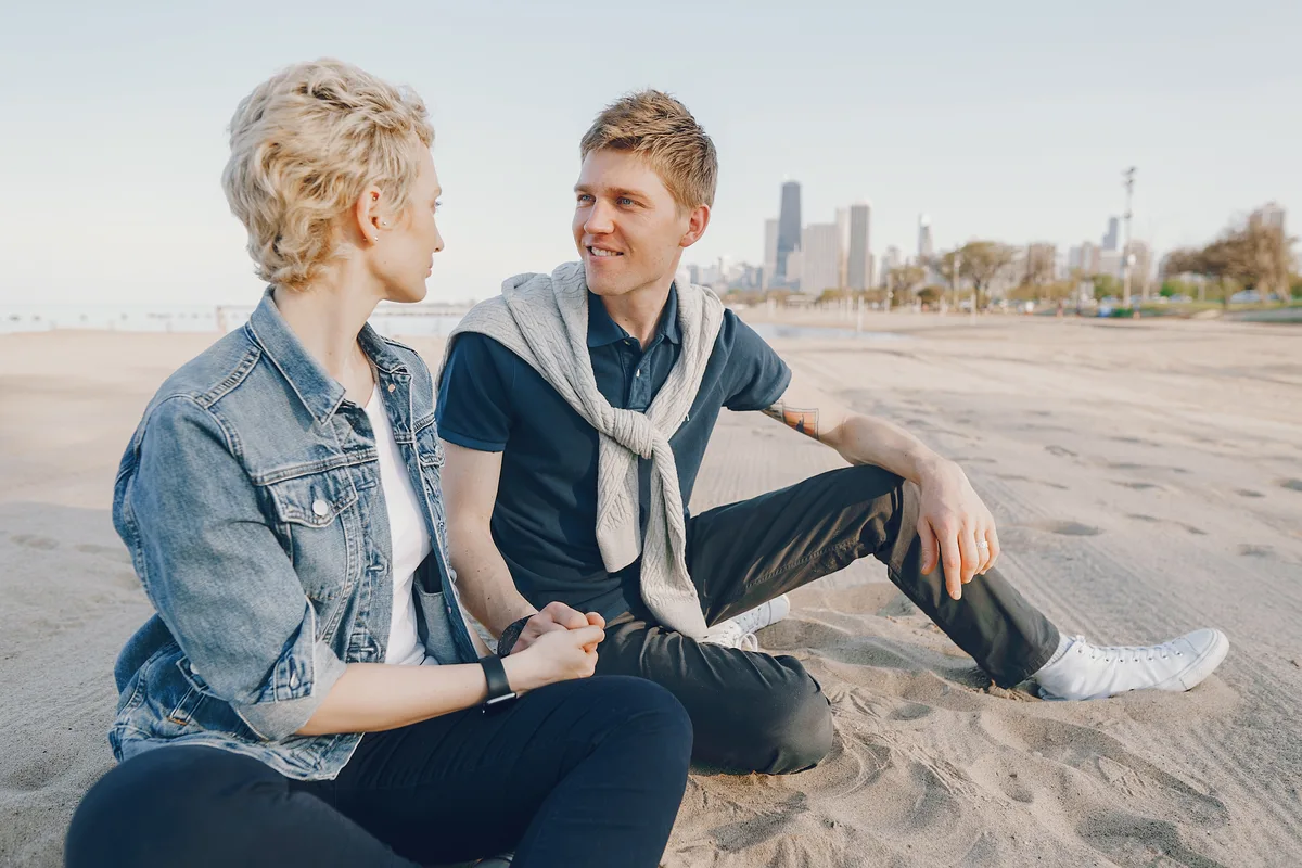 Couple sitting on a lakefront beach with the Chicago skyline behind them