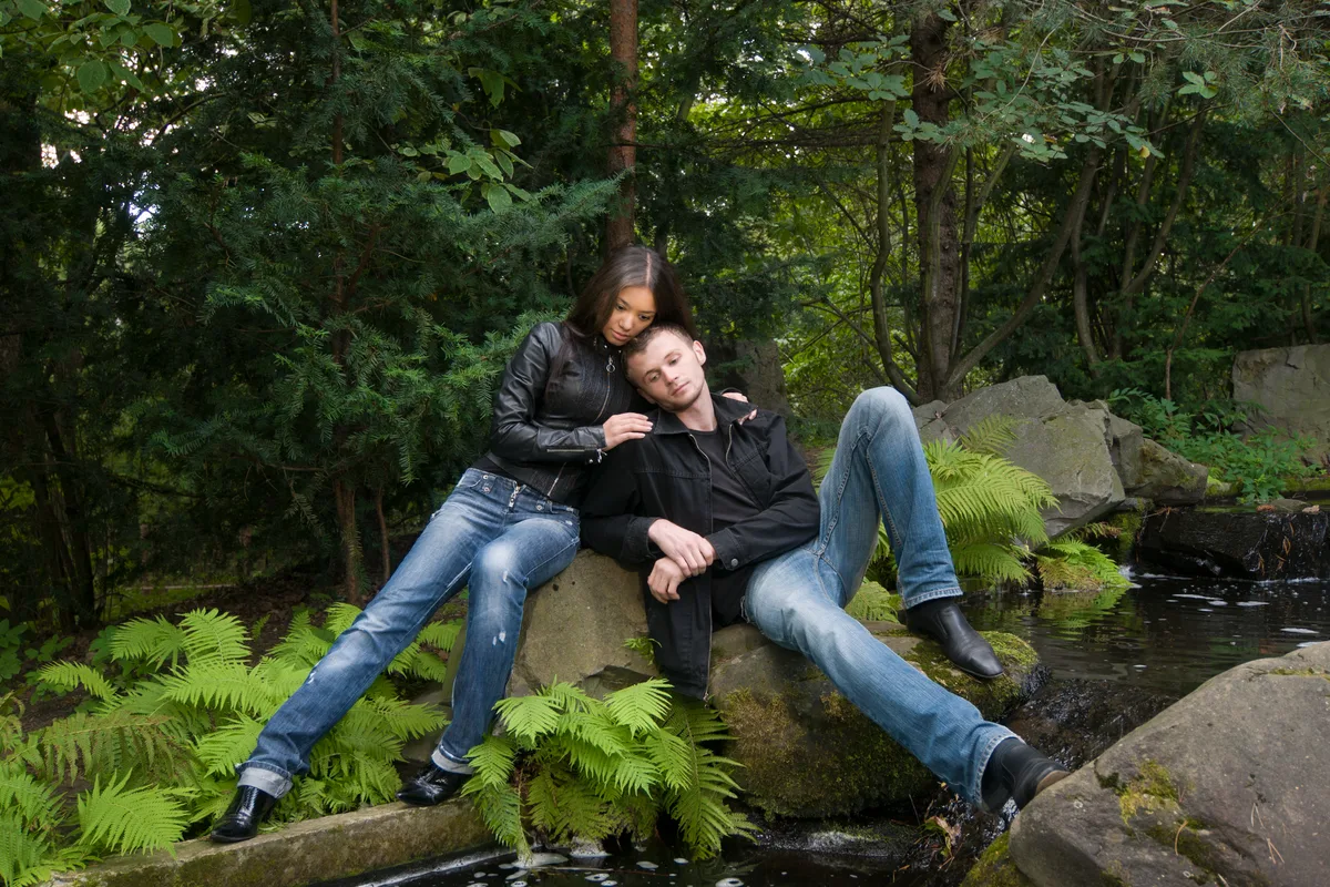 Couple resting on mossy rocks in a green forest