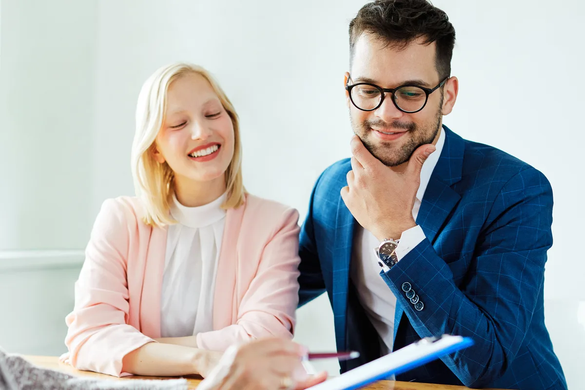 Couple reviewing papers with an advisor holding a blue folder