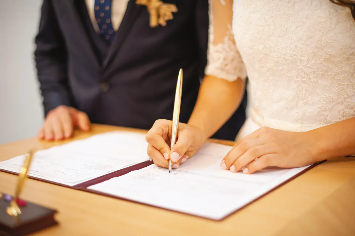 Close-up of a hand signing a written agreement with a pen