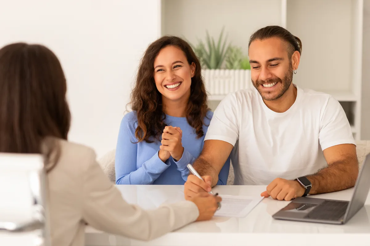 Couple signing papers across the table from an agent