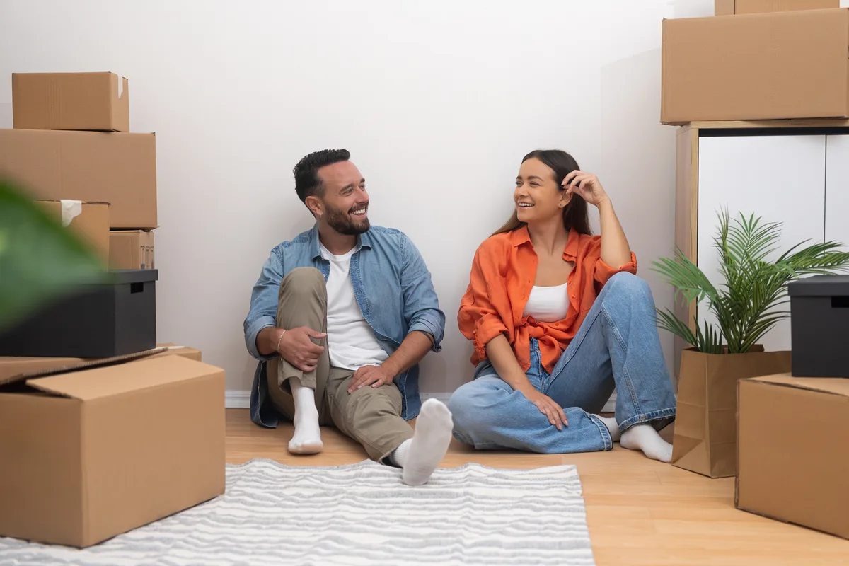 Couple sitting on the floor of their new home with moving boxes
