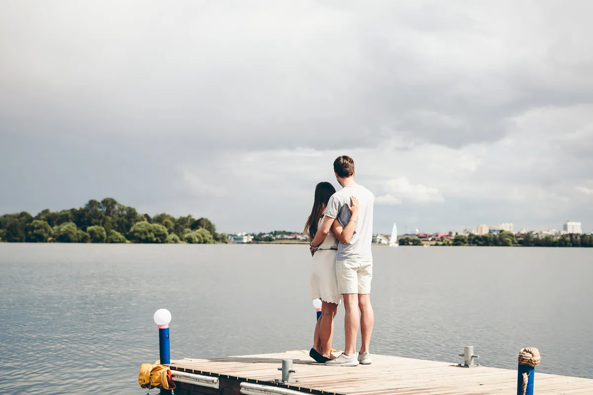 Couple standing together at the end of a dock on a wide lake