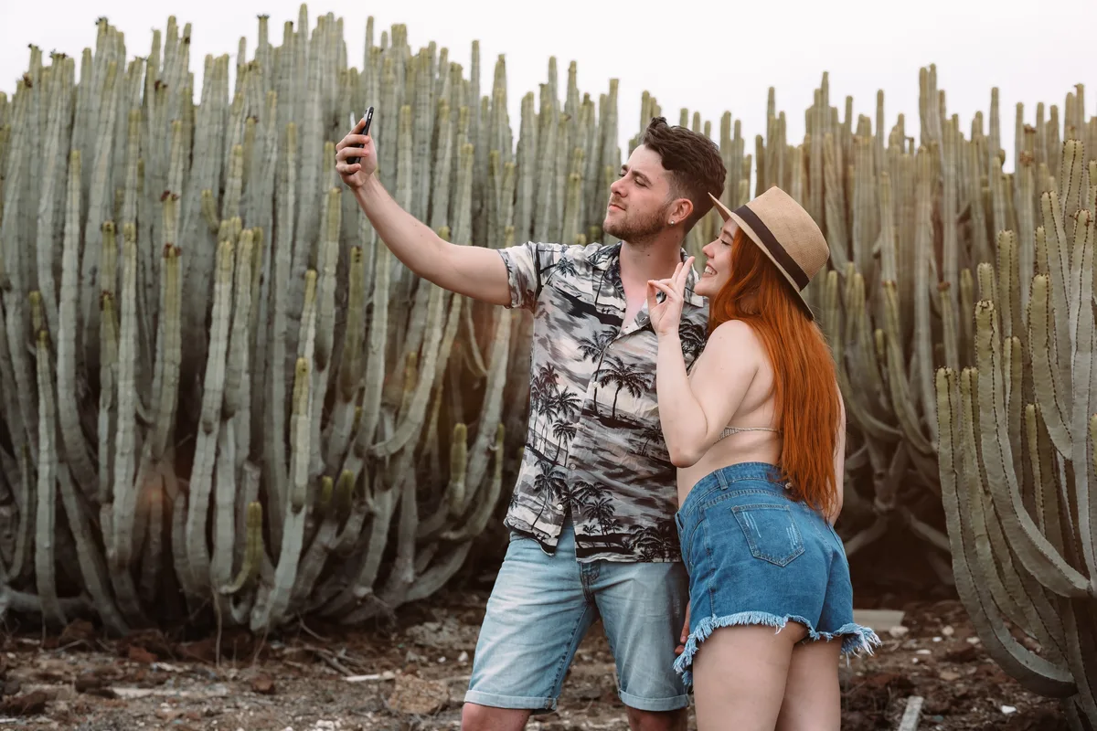 Couple taking a selfie in front of tall cactus plants