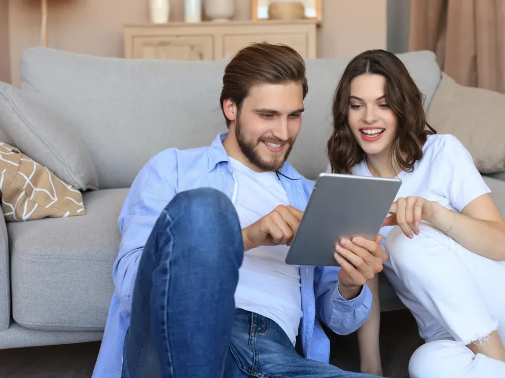 Couple looking at a tablet together on a gray sofa