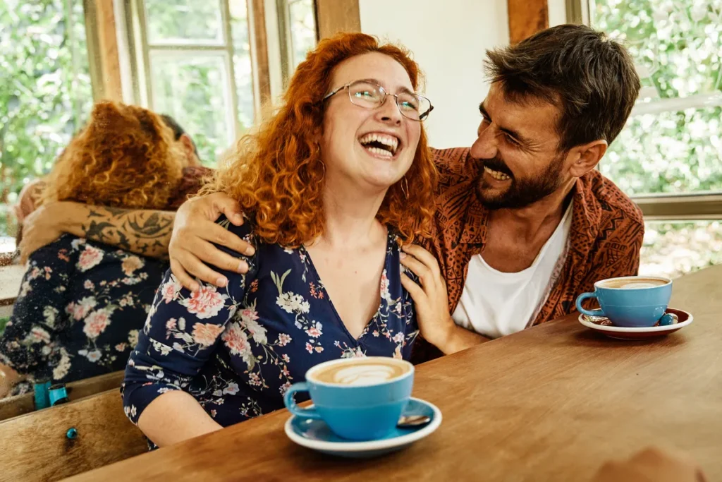 Couple laughing together over coffee in a cafe