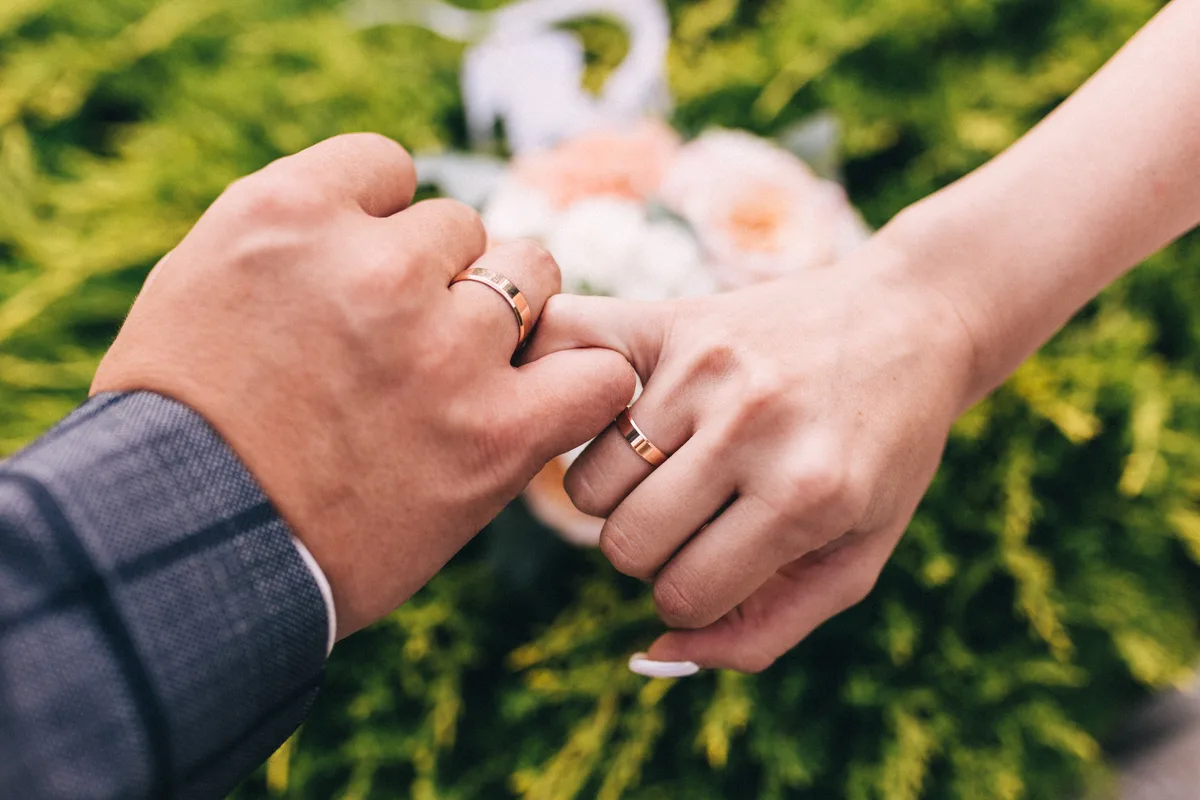 Close-up of a newlywed couple holding hands with wedding rings