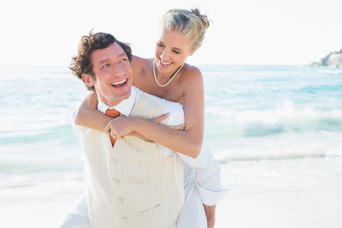 Laughing newlyweds on the beach on their wedding day