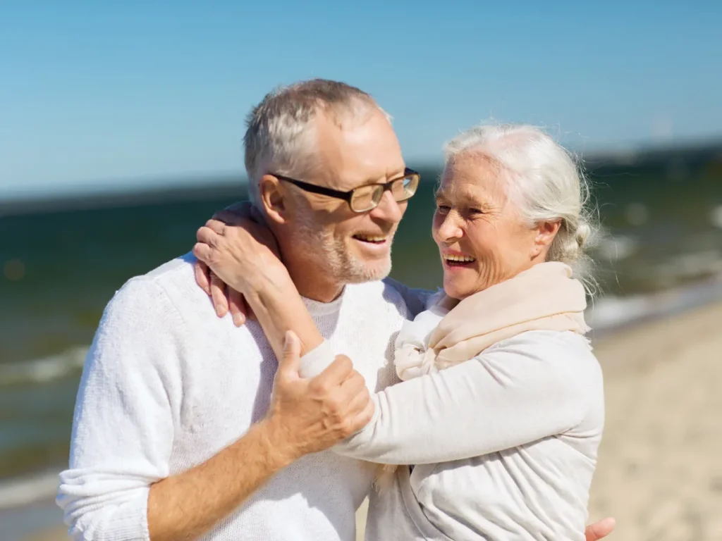 Older couple hugging and smiling by the sea